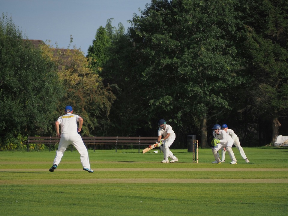 Cricketers in whites playing a match at a foundation-run ground