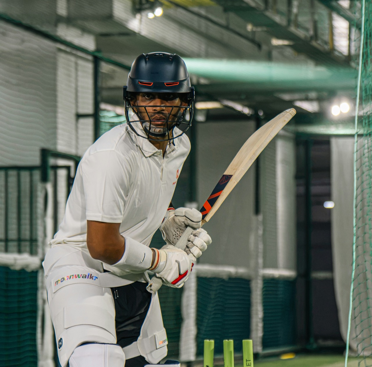 Batsman playing a shot during an organised cricket foundation match, wicketkeeper and fielder behind